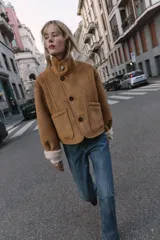 Cazadora reversible de cuello subido y manga larga, confeccionada en tejido efecto borreguillo con detalles en contraste efecto ante. Cuenta con cierre frontal de botones y bolsillos delanteros.