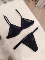 Conjunto de lencería compuesto por un corpiño triangular de microtul transparente con detalles de encaje en las copas y una tanga regulable con elástico ancho.