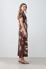 Vestido midi marrón con estampado floral blanco, cuello mao, manga corta y lazo ajustable en la cintura.