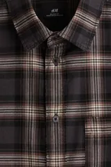 Camisa de manga larga con cuello inglés, tapeta clásica y canesú en la espalda. Presenta un bolsillo superior abierto y puños abotonados. El bajo es redondeado.