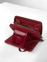 Mini billetera de cuero charolado color rojo, con cierre perimetral y solapa frontal con broche, decorada con un logo de búho grabado.