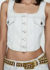 Chaleco estilo denim de corte crop, confeccionado en algodón. Presenta escote cuadrado, cierre frontal con botones metálicos y dos bolsillos con solapa en el pecho.