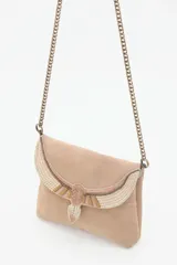 Cartera de mano o bandolera pequeña de gamuza negra con solapa decorada con un bordado artesanal en tonos dorados y beige que simula un pájaro con alas extendidas. Posee cadena metálica color dorado viejo y cierre magnético.