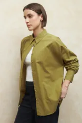 Camisa de corte clásico y holgado, confeccionada en tela blanca, con cuello camisero, cierre frontal de botones de nácar y mangas largas con puños abotonados.