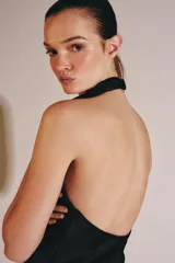 Top de cuello halter con escote fluido y caída suave. Presenta cierre con botones en la parte posterior y diseño sin mangas.