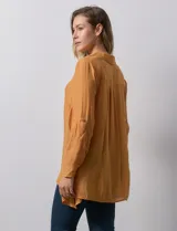 Camisa larga de rayón, con cuello clásico, cierre frontal con botones y mangas regulables con presilla. Presenta un diseño holgado con tajos laterales en el ruedo.