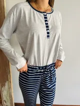 Pijama de algodón compuesto por una remera gris de manga larga con cuello redondo y tapeta de botones azul marino, y un pantalón largo a rayas horizontales azul marino y blanco con cintura elastizada y lazo de ajuste.