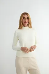 Buzo de punto color crema con cuello alto, manga larga y puños y ruedo acanalados.