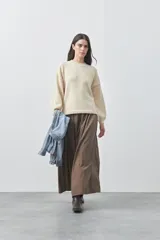 Sweater de tejido liviano con silueta relajada, hombros caídos y mangas largas con puños ajustados. Presenta cuello redondo y lazos ajustables en el bajo.