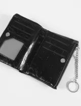 Billetera tarjetero de cuero vegano color verde petróleo con acabado brillante y texturizado. Cuenta con doble cierre metálico y logo plateado en la parte frontal.