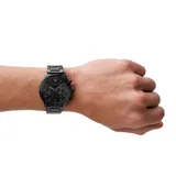 Reloj cronógrafo Emporio Armani modelo Mario, con caja y pulsera de acero inoxidable en color negro. Presenta una esfera negra con índices y manecillas a tono, función de cronógrafo y ventana de fecha.