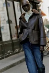Chaqueta de cuello solapa y manga larga, con diseño de doble faz que combina tejido efecto ante y borreguillo. Cuenta con cierre frontal de botones y bolsillos delanteros.
