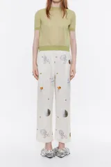 Pantalón tobillero de viscosa con textura y estampado de motivos espaciales. Modelo de corte carrot, con cierre de cremallera frontal y bolsillos laterales. Pinzas en delantero y cinturilla fruncida en el trasero.