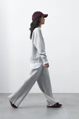 Pantalón de corte holgado y pierna ancha, con cintura elástica ajustable mediante cordón. Presenta bolsillos laterales y costuras verticales decorativas que recorren el frente de las piernas.