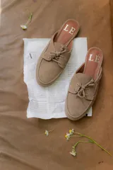 Mules de gamuza color tostado con diseño de zapato náutico, con cordones frontales y plantilla con logo estampado.