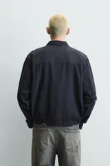Cazadora de estilo cropped confeccionada en tejido de algodón con estructura canvas. Presenta cuello solapa, cierre frontal con cremallera y manga larga con puños abotonados. Incluye bolsillos asimétricos de plastrón en el pecho y bolsillos laterales, con un acabado de lavado efecto rotos en toda la prenda.