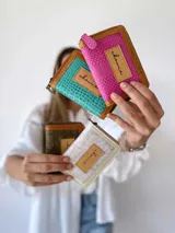 Billetera pequeña de cuero turquesa con textura de reptil y detalles en cuero marrón. Tiene cierre metálico y monedero interno.