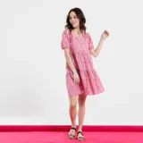 Vestido corto con estampado floral en tonos rosados y violetas, escote cuadrado y mangas cortas abullonadas.