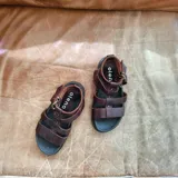 Sandalias de cuero marrón con tiras anchas y hebilla lateral.