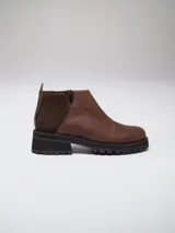 Botinetas negras con suela track, combinando cuero texturizado en la parte frontal y cuero charolado en la parte trasera. Diseño de caña baja con detalle de corte lateral.