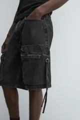 Bermuda de corte relajado en denim de algodón color beige, estilo cargo, con cinco bolsillos y bolsillos plastrón con solapa en las perneras.