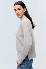 Polera tejida de punto confeccionada en lambswool color gris claro, con cuello alto y calce holgado.