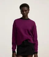 Suéter negro de punto leve, corte boxy, cuello redondo y mangas largas con puños y bajo acanalados.