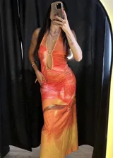 Vestido midi de corte al cuerpo con estampado abstracto en tonos naranja, amarillo y rosa. Tiene escote halter con abertura en el pecho y espalda descubierta.