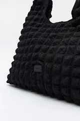 Cartera marrón con textura acolchada y efecto tridimensional. Diseño blando con asa fruncida.