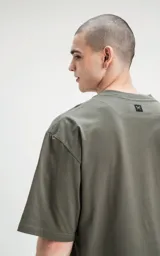 Remera de algodón premium color verde militar, con corte oversize, hombros caídos y cuello redondo.