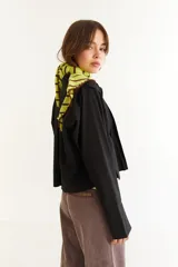 Blusa blanca de algodón con cuello mao y tablas verticales en el frente que crean un efecto de volumen. Presenta cierre frontal con botones y mangas largas.