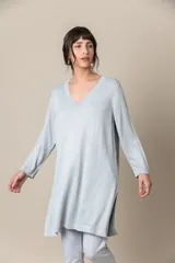 Buzo celeste de hilo metalizado con escote en V con apliques de tallas, manga tres cuartos y tajos laterales.