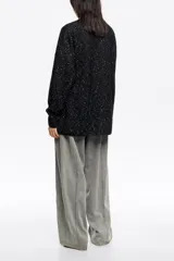 Cárdigan largo de punto negro con efecto jaspeado (neps) en blanco, de corte oversize, escote en pico pronunciado, manga larga y bolsillos de plastrón.