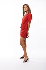 Vestido corto rojo con escote redondo, mangas cortas y solapas decorativas con botones metálicos en el frente.