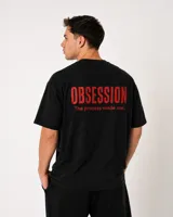 Remera oversize negra de 100% algodón, con cuello redondo, manga corta y estampado frontal y dorsal en color rojo con la frase "OBSESSION The process made me.".