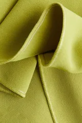 Top sin mangas de punto interlock pesado, con escote en V tanto en el frente como en la espalda. Presenta un diseño entallado con pliegues cosidos que se abren en la parte inferior creando un efecto peplum con vuelo.