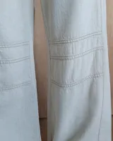 Pantalón de algodón color arena, de corte recto y holgado, con cintura elástica y detalle de costuras horizontales decorativas en la parte inferior de las piernas.