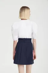 Minifalda azul marino de tela tecnológica con cierre frontal con cremallera, lazo en la cintura y bolsillos laterales con cierre.