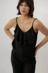 Musculosa negra con escote en V, breteles finos regulables y doble volado frontal con pespuntes.