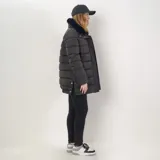 Campera puffer negra de corte largo, con diseño de canelones horizontales. Presenta cuello alto con detalle de pelo sintético extraíble, cierre frontal con botones a presión, puños y bolsillos laterales. Incluye aberturas laterales con botones para mayor comodidad.