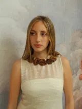 Vestido largo de punto color blanco con sutil brillo, escote redondo adornado con flores de cuero genuino y espalda descubierta.