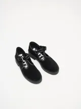 Zapatos tipo guillermina de gamuza color bordó, con diseño de tira en T, cierre con hebilla metálica y costuras a la vista en hilo blanco. Poseen una suela de plataforma de goma negra de 4 cm.