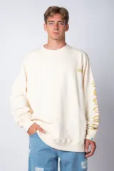 Buzo oversize de cuello redondo en color crema, confeccionado en tela rústica. Presenta un pequeño logo estampado en el pecho y una serie de ilustraciones de empanadas con sus respectivos nombres impresas a lo largo de la manga izquierda.