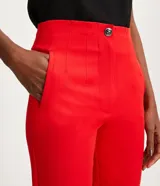 Pantalón zanahoria de sastrería color blanco, con cintura alta, trabillas y botón contrastante.