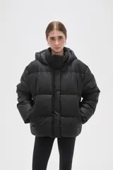 Campera puffer negra con capucha, diseño capitoneado y cierre frontal oculto. Presenta un corte holgado y bolsillos laterales.