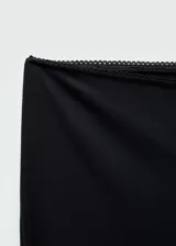 Leggings negros de corte entallado con aberturas en el bajo y detalle de puntilla en la cintura. Cuentan con cierre lateral invisible.