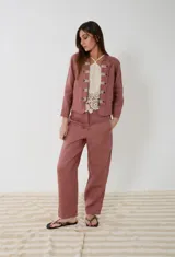 Pantalón sastrero de lino color rosa viejo, de tiro medio con corte flojo en las piernas que se afinan hacia los tobillos. Cuenta con bolsillos frontales con detalles de pasamanería a rayas.