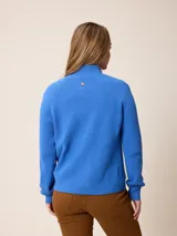 Cardigan de punto color azul, con cierre frontal completo, cuello alto y mangas largas con puños acanalados.