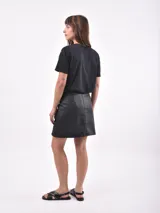 Falda corta de cuero sintético color negro, con corte recto y una pequeña abertura frontal.