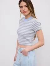 Remera crop de punto a rayas horizontales en tonos gris, blanco y celeste, con cuello redondo y mangas cortas.